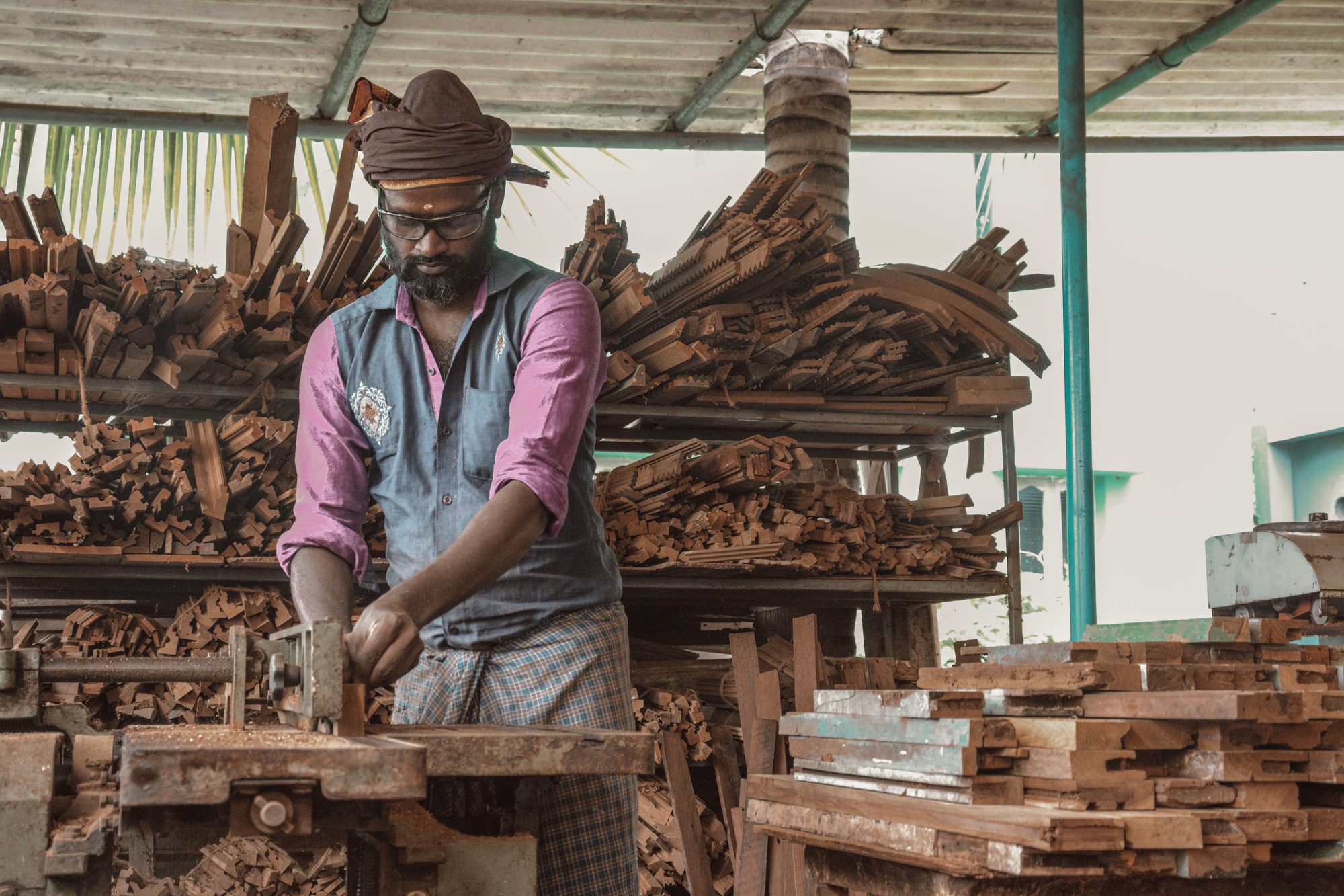 Every bespoke piece begins here — in the timber yard, with a craftsman who has carved this motif hundreds of times before.